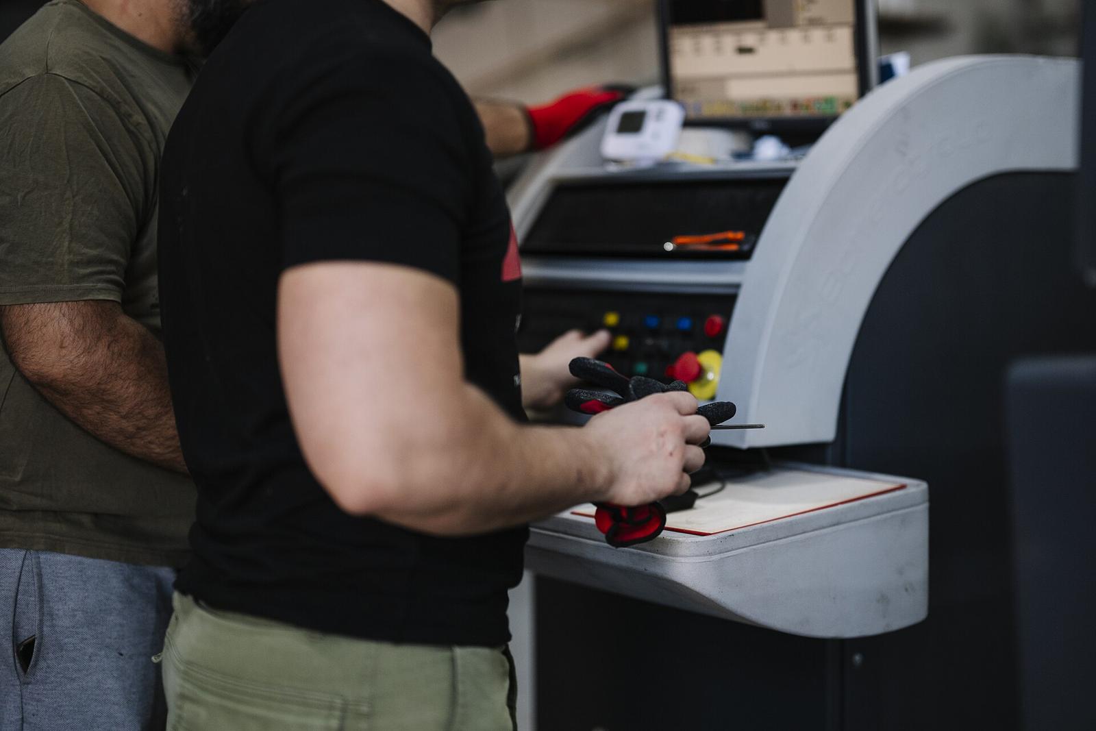 Two workers at a machine control panel