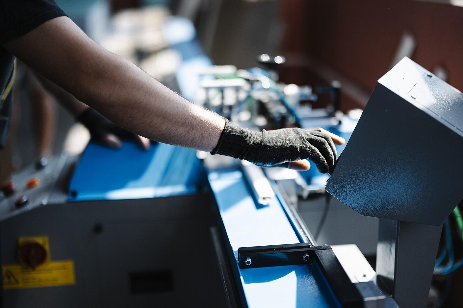 An operator's gloved hand on a machine on a production line